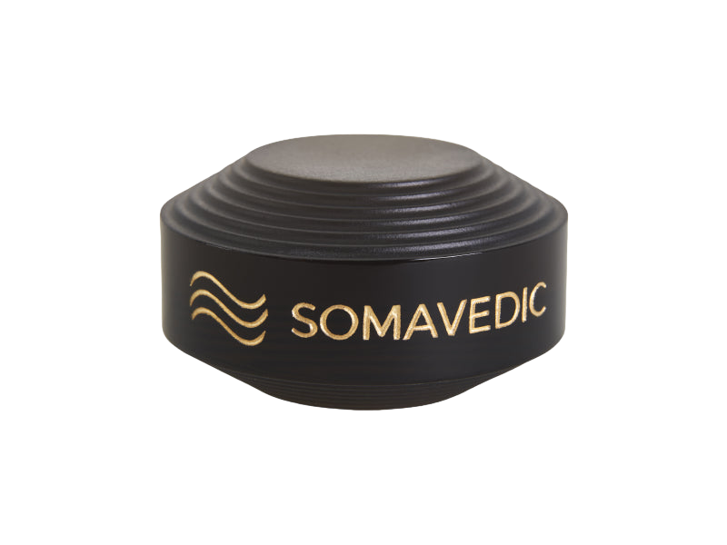 A sleek, modern gadget from Somavedic USA, the "Tiny" is a black, circular device with ridged sides and a gold logo accompanied by the word "SOMAVEDIC" in gold letters. It features a smooth, flat top and is designed to create a charged protective field wherever it's placed.