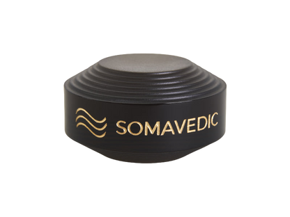 A sleek, modern gadget from Somavedic USA, the "Tiny" is a black, circular device with ridged sides and a gold logo accompanied by the word "SOMAVEDIC" in gold letters. It features a smooth, flat top and is designed to create a charged protective field wherever it's placed.