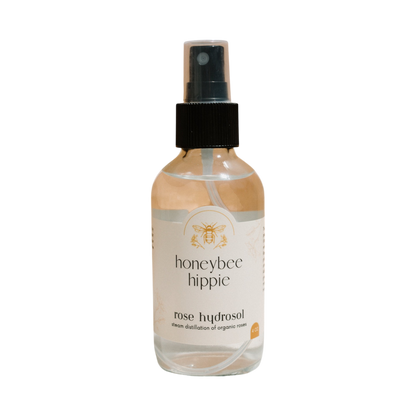 Honeybee Hippie's rose hydrosol is presented in a clear spray bottle with a black nozzle and bee logo. Steam distilled from organic roses, it's your ideal pores cleanser and moisture booster in one elegant spritz.