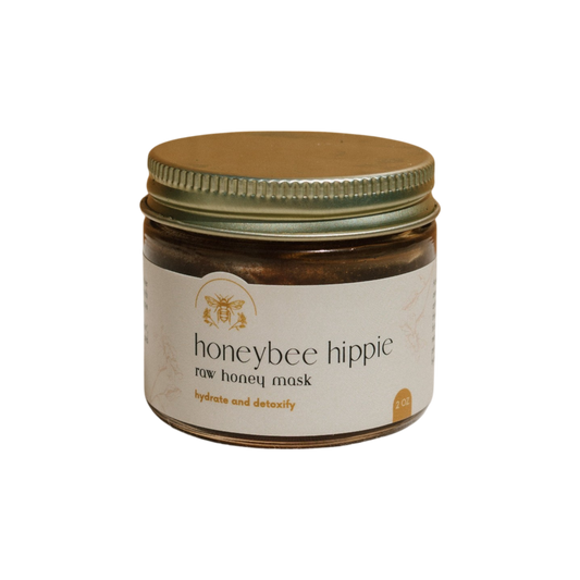 The Honeybee Hippie "herbal infused raw honey mask" comes in a small glass jar with a gold lid featuring a bee illustration. The label claims to hydrate, detoxify, and treat acne. Inside is a rejuvenating 2 oz portion of this wonderful mask.