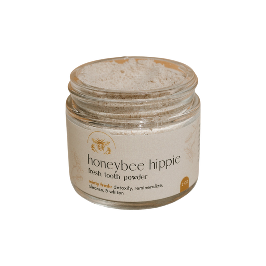 Honeybee Hippie's fresh tooth powder detoxifies, whitens, and remineralizes teeth while delivering minty freshness. A partially filled jar holds this revitalizing formulation designed to cleanse your smile.