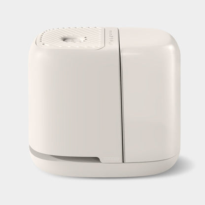 The Canopy Bedside Humidifier 2.0 is a modern, minimalist humidifier with an ivory, rounded design and a perforated top for mist release. Set against a light gray background, it seamlessly combines style and functionality.