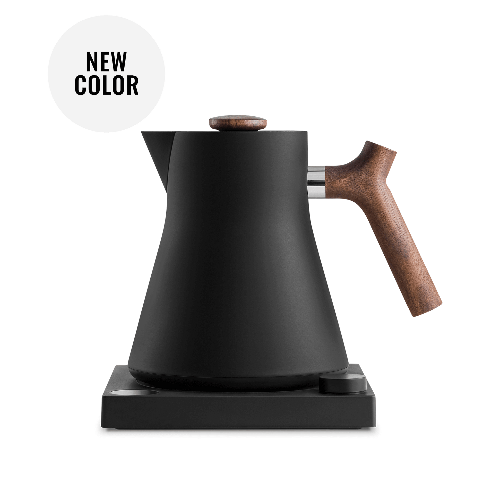 The Corvo EKG Electric Kettle by Fellow Wholesale, with its sleek matte black finish and wooden handle and knob, is elegantly perched on its square black base. Precision engineered, it boasts variable temperature control. The image emphasizes the kettle's minimalist design and includes a white circle noting "NEW COLOR.