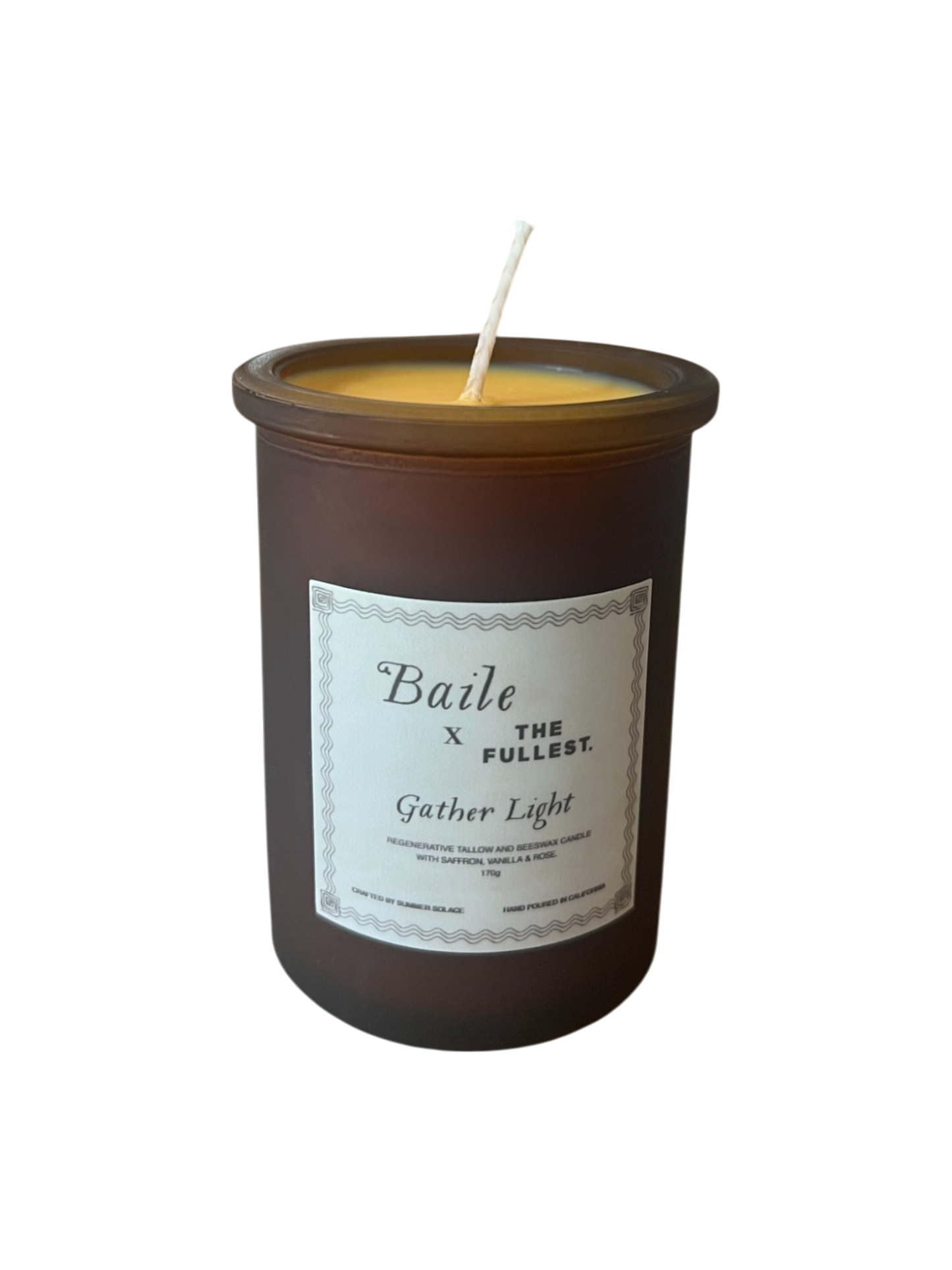 The "Gather Light - Saffron Beeswax Tallow Candle" by Baile is a brown, non-toxic candle with a single wick in a minimalist glass container. Infused with healing saffron, it promotes wellness and adds elegance to any space.