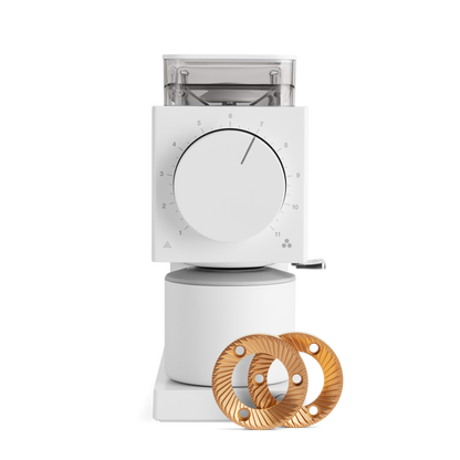 The Ode Brew Grinder from Fellow Wholesale is a white electric coffee grinder featuring a numbering dial on the front, set to 7. It comes equipped with Gen 2 Brew Burrs and offers 31 grind settings for precision. The grinder includes a transparent bean hopper on top and a small handle on the side, with two golden burr grinder plates displayed in front of the machine.