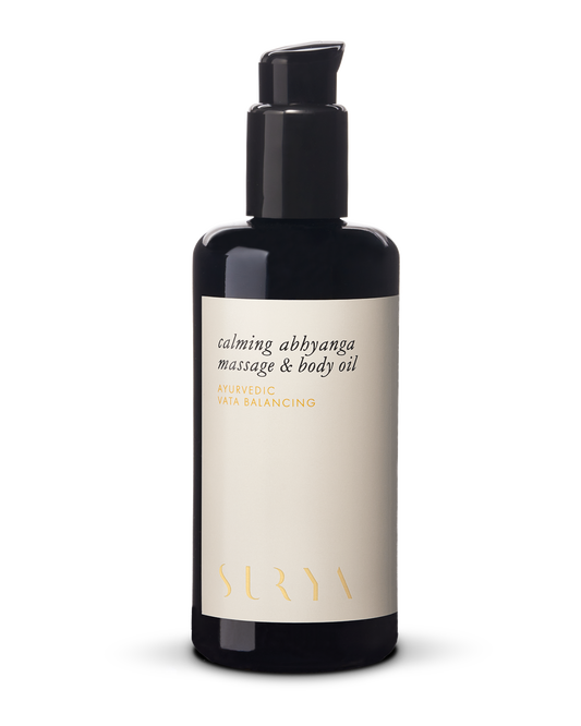 A black pump bottle labeled "Calming Massage & Body Oil," featuring a cream-colored label that reads "Ayurvedic Vata Balancing" and highlights organic ingredients like Ashwagandha Root, with the brand name "Surya" prominently displayed at the bottom in gold letters.