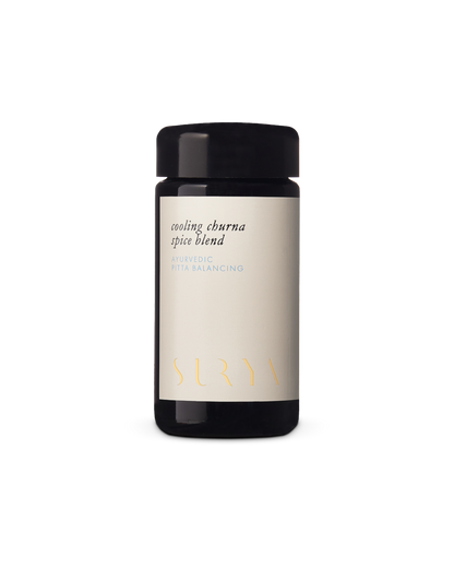 A dark glass jar labeled "Cooling Digestive Spice Blend" proudly bears the brand name "Surya," with its minimalist design and cream-colored label elegantly conveying a sense of tranquility and wellness.