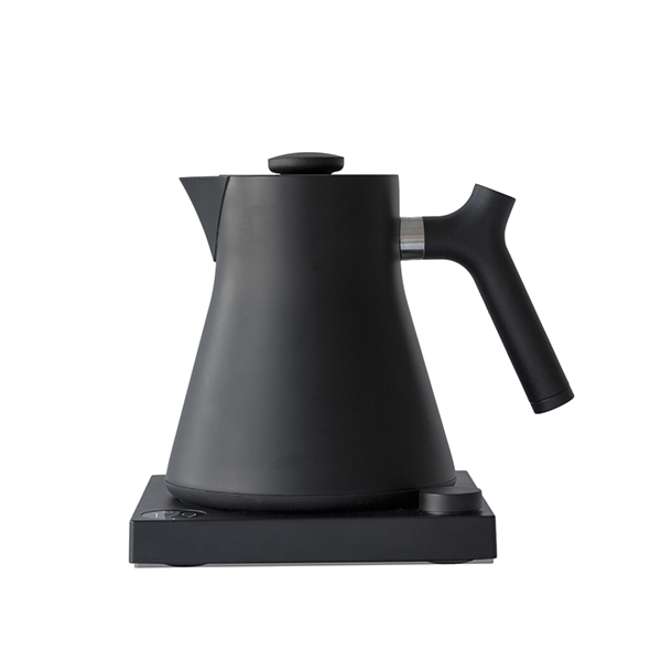 The Corvo EKG Electric Kettle by Fellow Wholesale stands on its matching base, boasting a sleek matte black finish and a modern, minimalist design. Precision engineered, this kettle features a tall, conical shape with a sturdy angled handle and a small spout. It seamlessly blends function and style while offering variable temperature control.