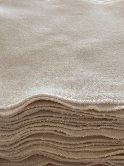 A close-up view of the neatly stacked light beige Organic Washcloth Set of 4 from cabane childrenswear, made from undyed organic cotton, showcasing their soft and smooth texture. The folded edges of the washcloths form uniform layers, highlighting their plushness and clean, tidy appearance.