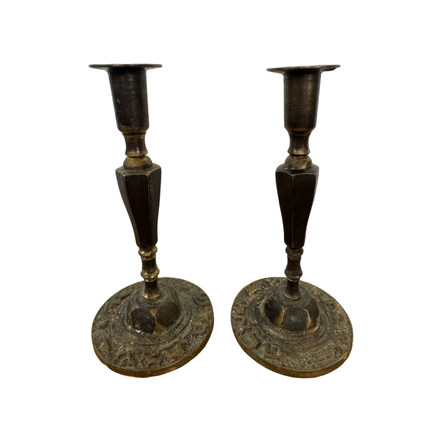 A pair of Shoppe Maison Vintage Shabbat Candle Holders with tall, tapered shafts and wide, circular bases featuring intricate etched designs, set against a black background. These brass candlesticks show signs of tarnish, adding to their antique appearance.