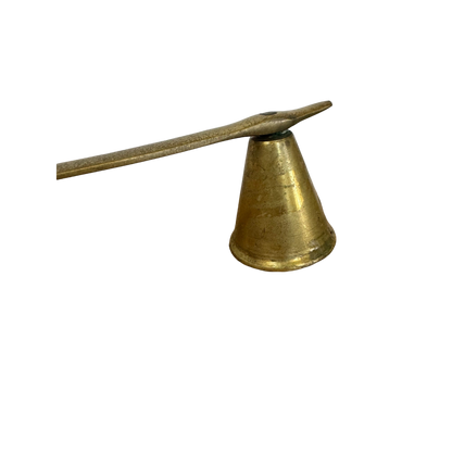 The Brass Candle Snuffer by Shoppe Maison is depicted against a neutral backdrop, showcasing its conical bell-shaped end. The tapered handle is artistically angled upwards, adding visual allure to its simple yet elegant design, making it a standout among vintage pieces.