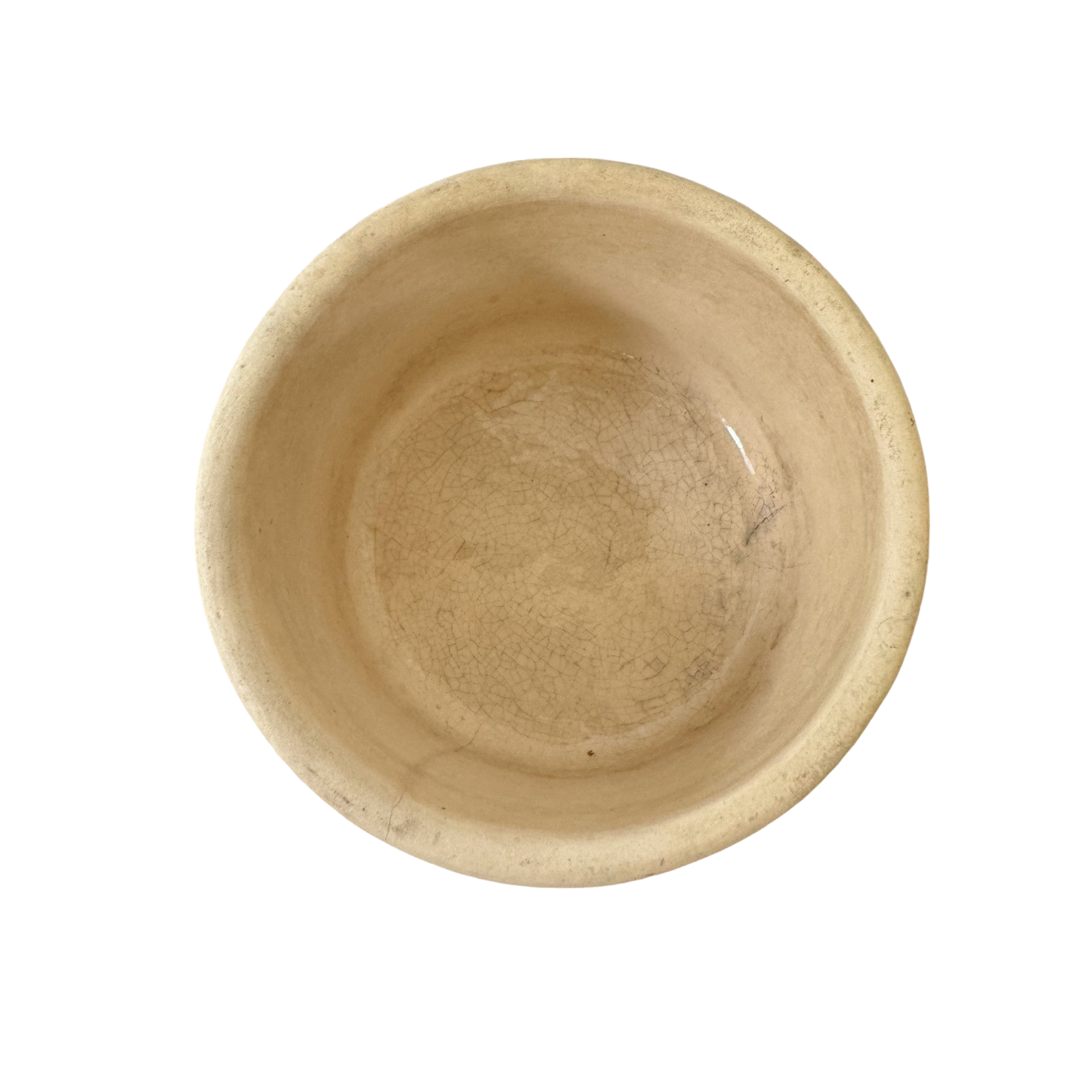 An empty round beige ceramic bowl with a slightly rough texture and visible cracks inside, viewed from above against a solid black background. Resembling the Vintage Small Stoneware Crock from Shoppe Maison, the bowl appears aged and weathered.