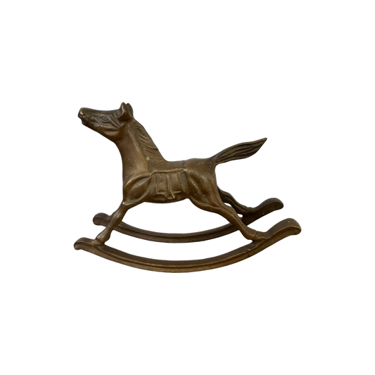 A bronze-colored mini Brass Rocking Horse sculpture from Shoppe Maison is pictured on a black background. The horse, depicted in mid-gallop with its front and hind legs extended, features a smoothly curved rocking base and boasts a vintage, classical design.