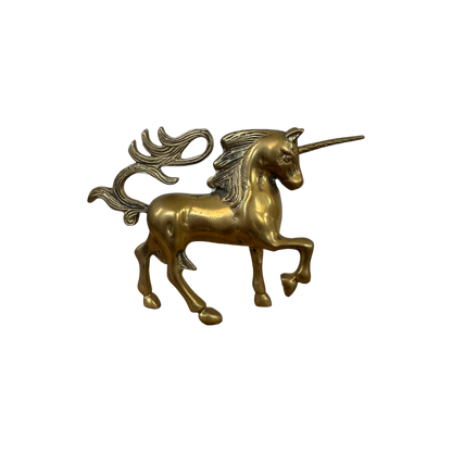 The Mini Brass Unicorn from Shoppe Maison is a gold-toned figurine, featuring a flowing mane and tail, standing on three legs with one front leg raised. Intricately detailed to emphasize its mythical nature, it is perfect for collectors of vintage goods and contrasts beautifully against a solid black background.