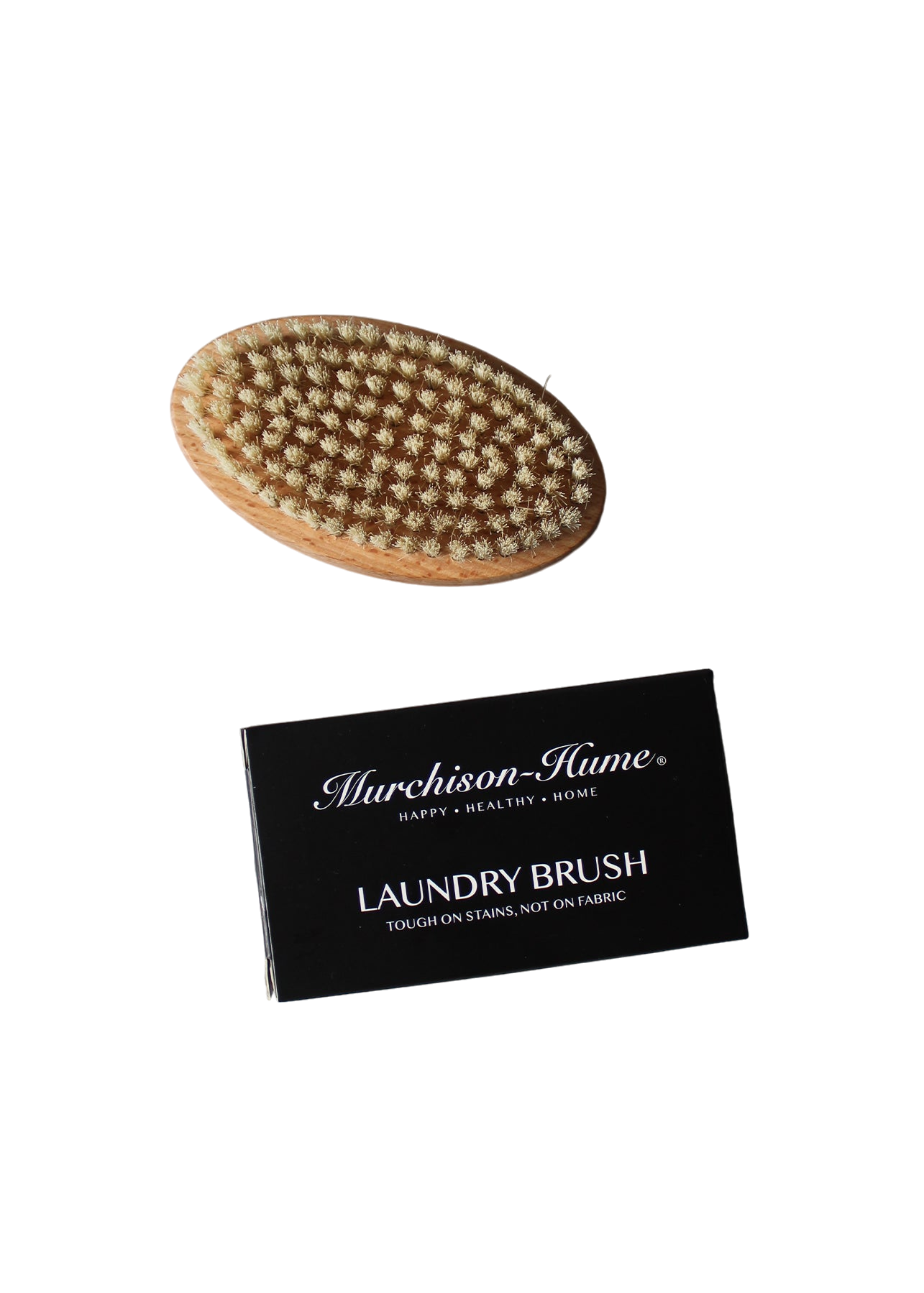 An oval-shaped brush with stiff natural bristles and a wooden base is placed above a black rectangular box labeled "Murchison-Hume Compostable Laundry Brush: Tough on Stains, Not on Fabric." The background is black.