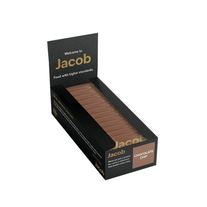 A black open box labeled "The Jacob Bar" from the Jacob Bar brand contains several brown rectangular chocolate chip snacks neatly arranged inside. The box promotes "Food with higher standards" and encourages, "Why not add a protein boost with a sweet treat that tastes great?" featuring Grass-Fed Whey Protein for added nutrition.