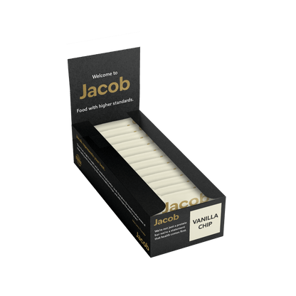 A black box prominently displaying the brand name "Jacob Bar" contains individually wrapped white chocolate bars labeled "The Jacob Bar - Vanilla Chip." Made with 100% Organic Cacao, the open box shows several bars neatly lined up inside. The tagline "Food with higher standards" is printed on the box.