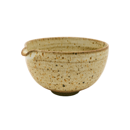 The Katakuchi Matcha Tea Bowl by Chafinity Tea is a beige ceramic piece featuring a small spout on one side, reminiscent of traditional Japanese bowl designs. Its speckled texture and slightly darker rim and interior pattern lend it a rustic charm. Set against a black background, this bowl embodies the essence of Japanese hospitality.