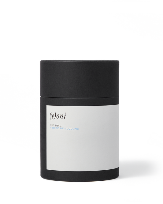 A cylindrical black container with a white label bearing the brand name "Surya" and the text "(y)oni reset steam ayurvedic pitta cooling." The cap is also black, and the background is a clean white. Perfect for promoting reproductive health, this (y)oni Reset Steam by Surya uses Ayurvedic herbs for natural balance.