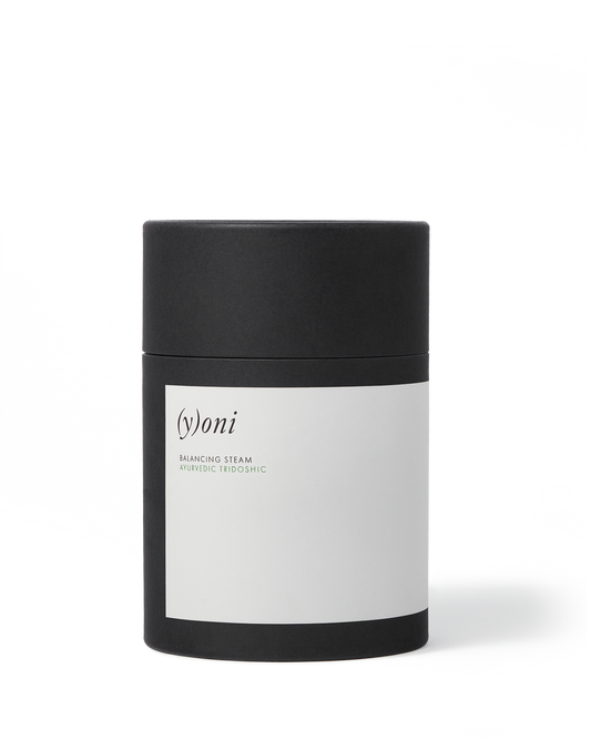 A cylindrical black and white container labeled "Surya (y)oni Balancing Steam." The minimalistic design features a simple white label against a sleek black background, emphasizing its blend of Ayurvedic herbs for hormone balance.