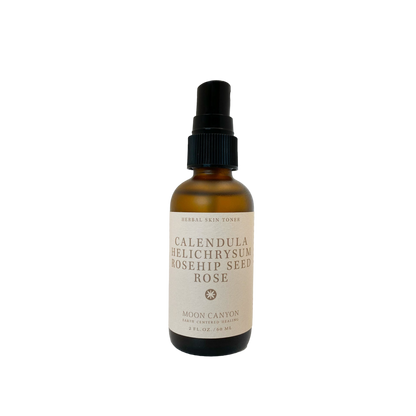 A brown glass bottle with a black pump dispenser labeled "Herbal Skin Toner" from Moon Canyon Healing features anti-inflammatory herbs such as Calendula, Helichrysum, and Rosehip Seed Rose. The 2 FL. OZ. / 60 ML bottle contains organic ingredients.