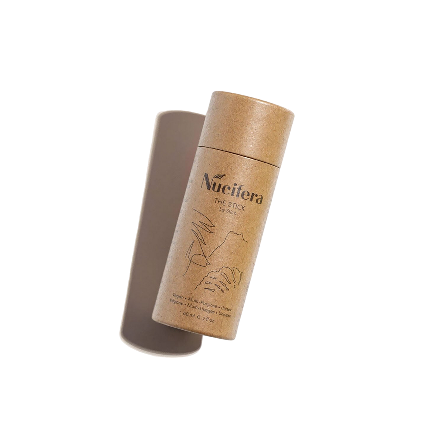 A cylindrical, eco-friendly cardboard container labeled "Nucifera The Stick" from Nucifera Body Store, featuring minimalist line art and holding a solid deodorant stick, is shown against a plain white background. As part of The Essentials Kit, this multi-purpose skincare product appears slightly angled with the lid propped open.