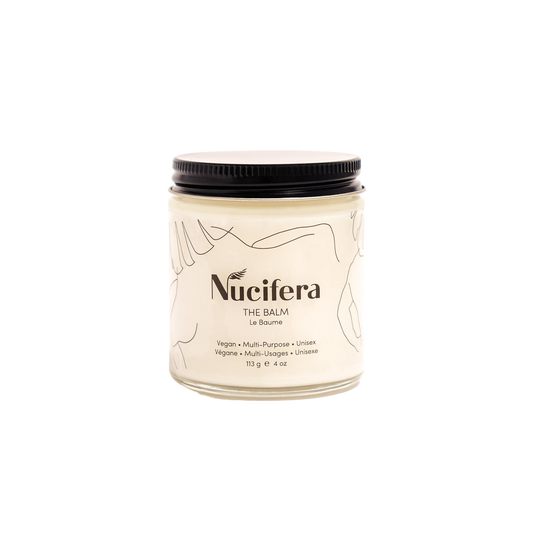 A jar of The Balm from Nucifera Body Store is shown against a white background. Designed to enhance skin tone and texture, this vegan and unisex product features a minimalist label with line art and a black lid. The container holds 113 grams (4 oz) of balm.