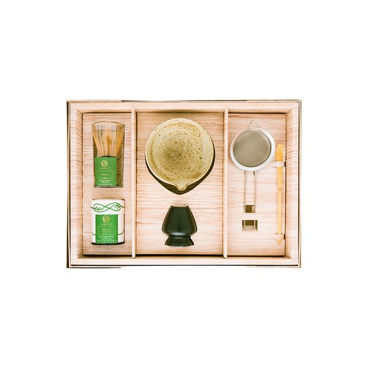 The Signature Matcha Collection Set from Chafinity Tea includes a green tea set in a wooden box, featuring a bamboo whisk, a container of matcha powder, a ceramic matcha bowl, a matcha sifter, a matcha scoop, and a whisk holder. Each item is neatly placed in its own compartment to enhance the experience of Japanese tea ceremonies.