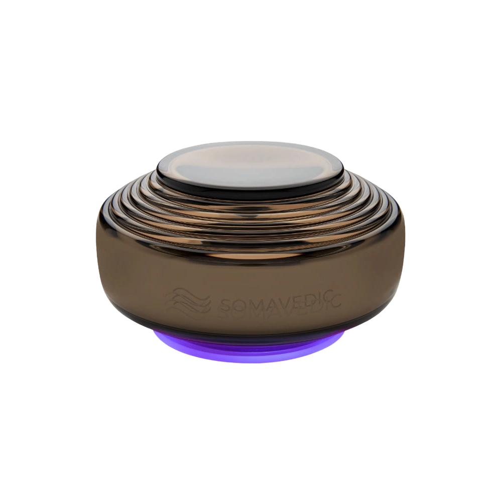 Anthracite-colored, dome-shaped electronic device with multiple concentric ridges, a smooth top surface, and a faint purple glow at its base. Designed to mitigate electromagnetic fields (EMF), the brand name "Somavedic USA" is subtly engraved on its side.