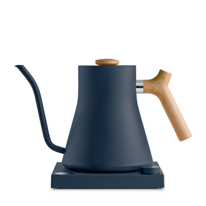 The Stagg EKG Electric Kettle from Fellow Wholesale is a sleek, matte black pour-over kettle boasting a precise gooseneck spout and a wooden handle. It rests gracefully on its base, showcasing a modern design with smooth curves, variable temperature control, and a minimalist aesthetic.