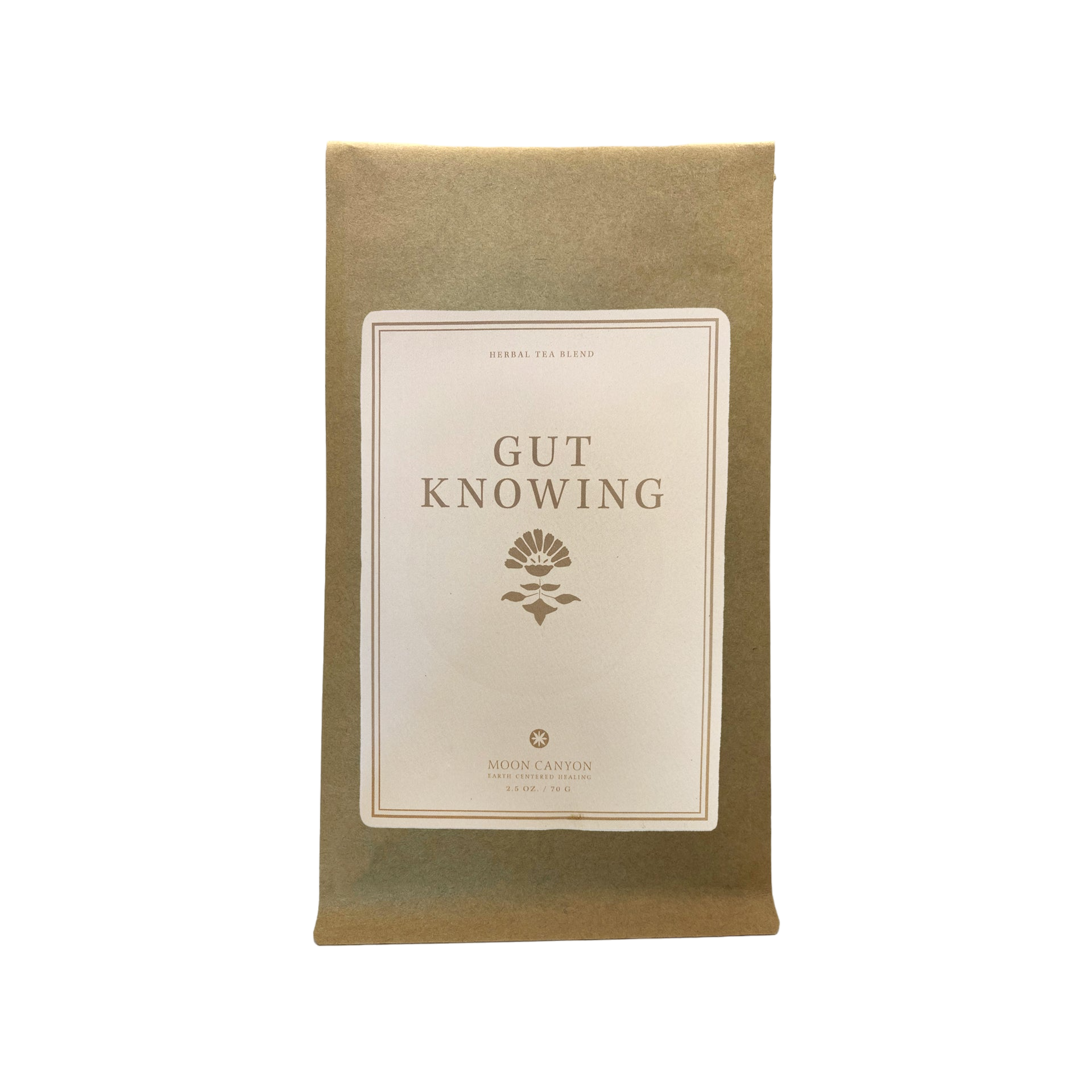 A brown paper package featuring a white label inscribed with "Gut Knowing Tea Blend" and adorned with a floral emblem. The label also presents "HERBAL TEA BLEND" at the top and "Moon Canyon Healing Los Angeles" at the bottom, emphasizing its support for mood and the gut-brain axis. The image is set against a black background.