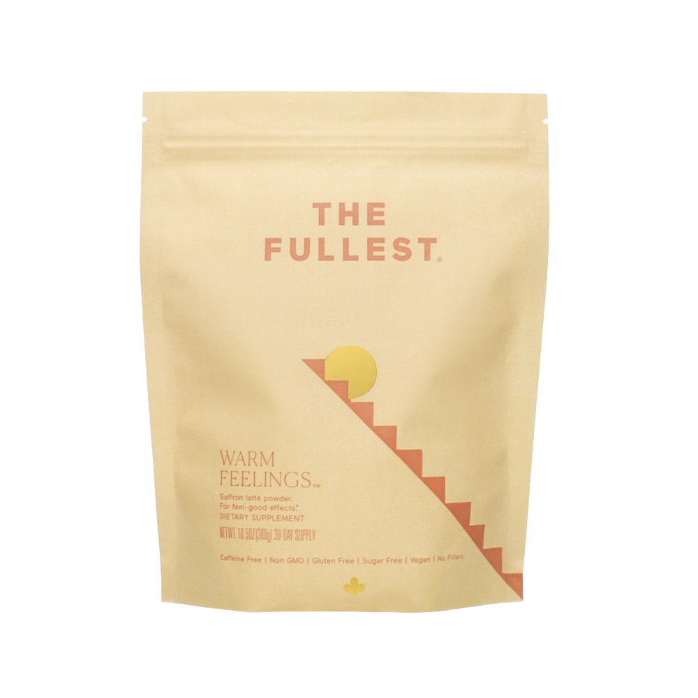 A pink/beige resealable pouch of THE FULLEST's "Warm Feelings® Saffron Latte - 30 Day Supply" dietary supplement features orange text. With a minimalist design that includes sun and staircase graphics, the product is designed to improve mood and promote restorative sleep. This non-GMO, gluten-free, sugar-free, vegan blend also offers a caffeine-free saffron latte mix.