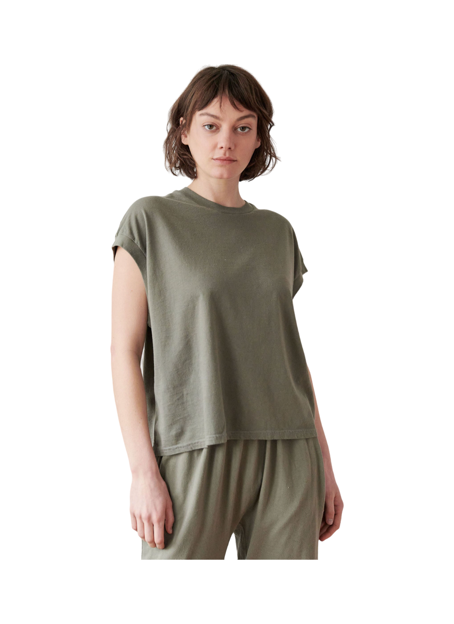 A person in a loose-fitting Organic Cotton Jersey Box Tee in Fir by Wol Hide and olive-green pants, stands against a plain backdrop with a neutral expression, showcasing a relaxed, casual style emblematic of the Made in USA ethos.