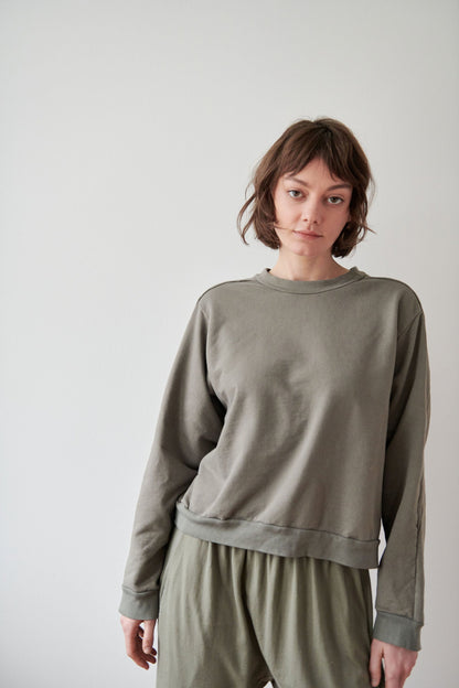 A person with short brown hair is wearing the Wol Hide Cotton French Terry Easy Summer Sweatshirt in Fir, along with matching pants made of Organic Cotton French Terry. They are standing against a plain white background, looking directly at the camera.