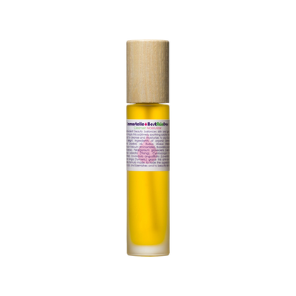 A small glass roll-on bottle filled with yellow liquid, labeled "Best Skin Ever Cleanser - Immortelle" by Living Libations, offers complexion perfection. The bottle, capped with wood, hints at a luxurious oil or serum ideal for those with skin sensitivities. Set against a plain white background, it promises gentle and effective skincare.