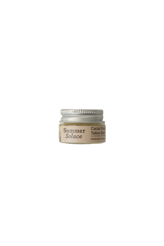 A small jar with a white lid, labeled "Summer Solace Tallow" and "Cacao Rose Cuticle, Lip, and Brow Balm - Regenerative Tallow™," serves as a multipurpose moisturizer. The jar is simple and minimalistic in design, featuring text on a beige background.