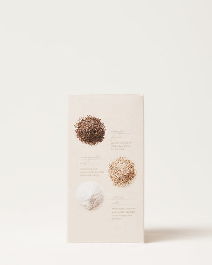 A beige package of Surya Calming Bath Soak is shown featuring three circular piles of powders. The text next to each pile describes: "Amla (top): Deadly winner for body and shining hair," "Ashwagandha (middle): Nourishing and strengthening powder with natural salts," and "Rasa Tauta (bottom): Moisturizes, cleanses.