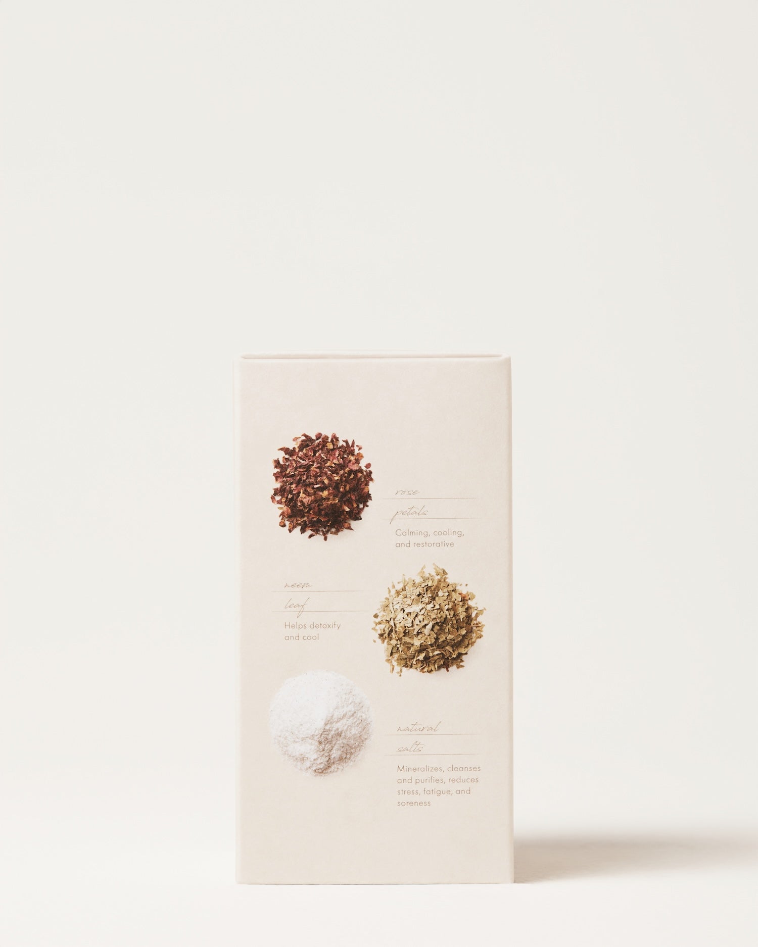 The Cooling Bath Soak by Surya comes in a beige box adorned with three distinct piles of herbs and powders on the front, ideal for your next Ayurvedic remedy. The top pile is brownish, the middle one light green, and the bottom pile white. Each pile has a description beside it on the box, though the small text may be difficult to read.