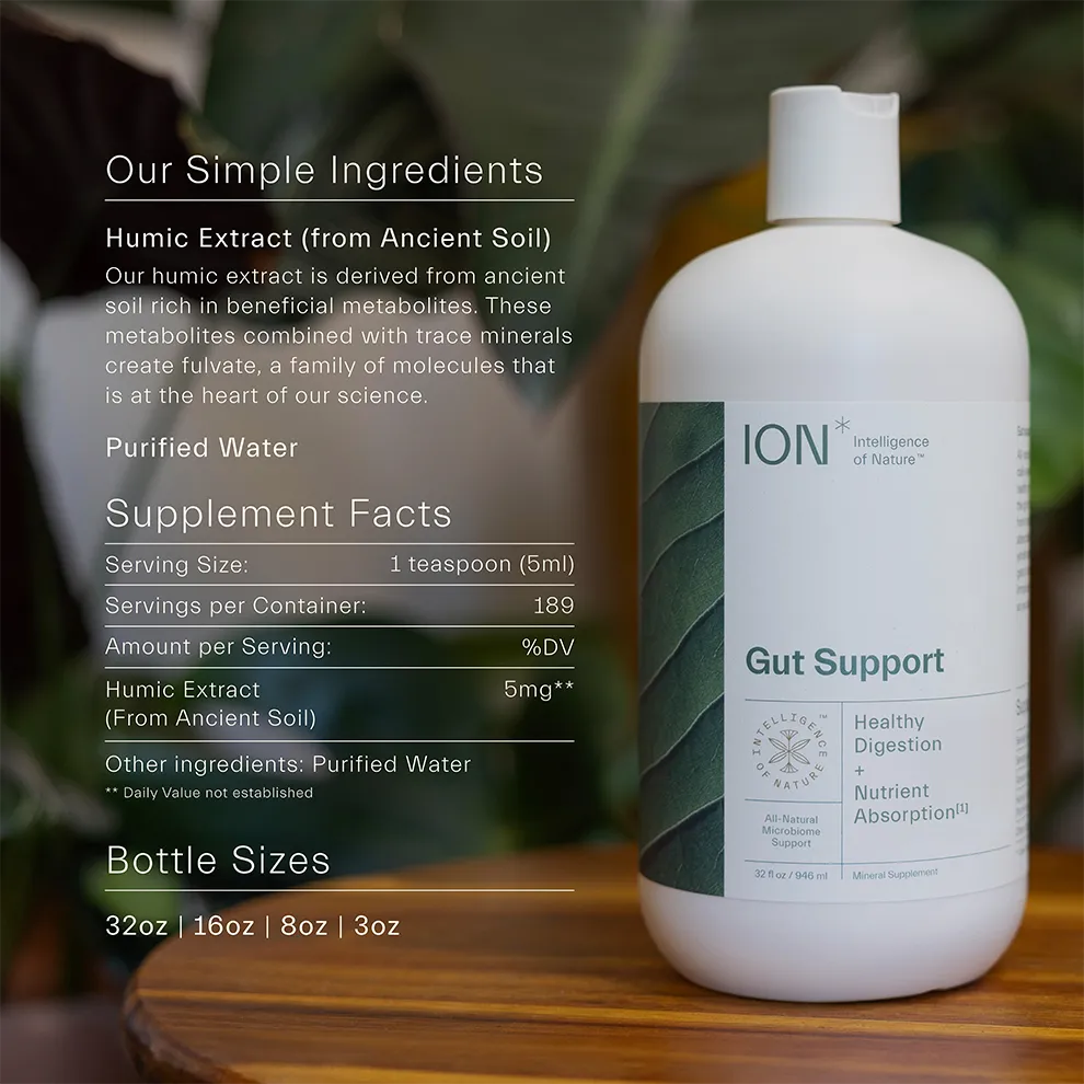 A bottle of ION* Gut Support rests on a wooden table in a natural setting. The label emphasizes its simple ingredients, which include humic extract from ancient soil and purified water. Designed to support gut health, each 5ml serving contains 5mg of humic extract to promote microbiome support.