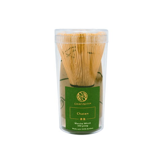 A 100-prong bamboo matcha whisk with finely spaced prongs is encased in a clear cylindrical container. The label on the container reads "Chasen Matcha Whisk 100-prong Made with 100% Bamboo" in green and gold text under the brand name Chafinity Tea, perfect for preparing ceremonial-grade matcha or Gyokuro green tea leaves.