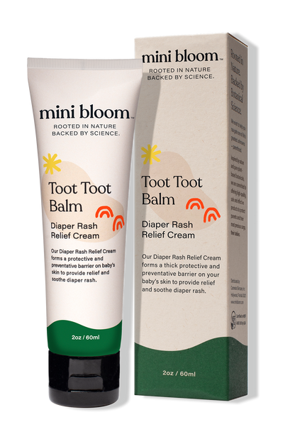 An image of a Mini Bloom Toot Toot Diaper Rash Balm tube and its box. The 2 oz (60 ml) tube offers a protective barrier to relieve diaper rash and soothe irritated skin. The packaging highlights that the product is both nature-rooted and science-backed.