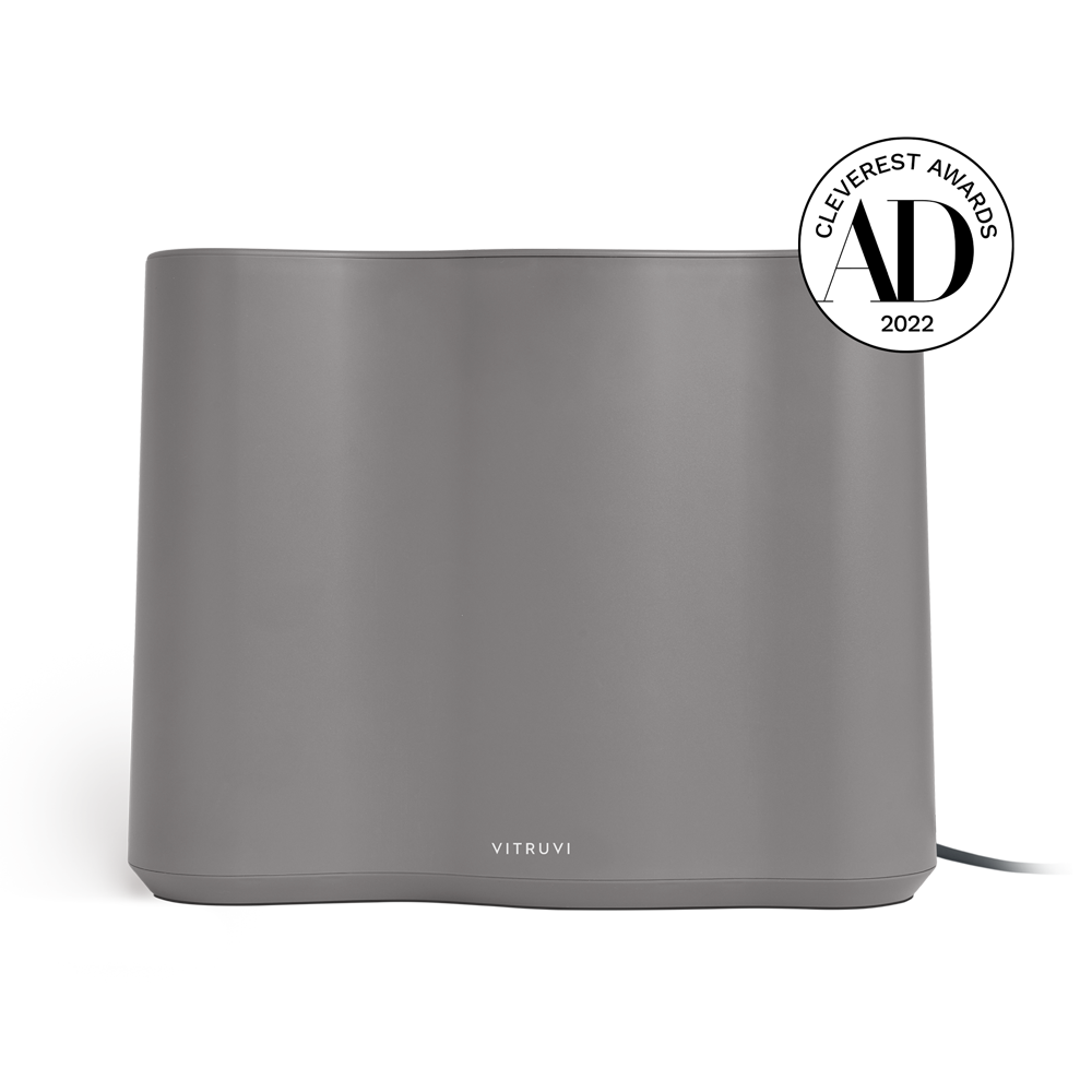 A sleek, gray Vitruvi Cloud Humidifier with a minimalist design, featuring the brand name "Vitruvi" on the front. Incorporating ultrasonic technology for enhanced performance, it has been awarded the 'Cleverest Awards 2022' by AD, as indicated by the badge displayed on the upper right corner.