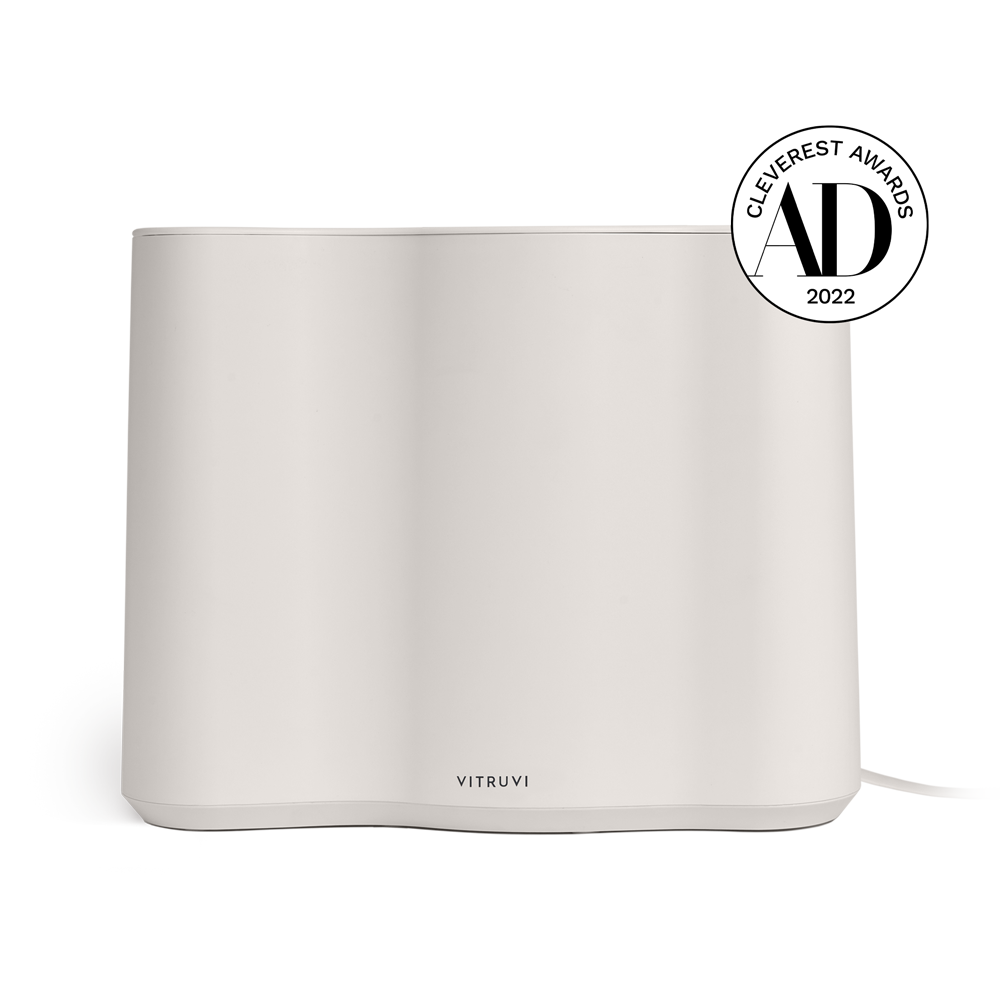 A sleek and minimalist Vitruvi Cloud Humidifier in a clean white finish is pictured. It boasts a smooth, curved design and utilizes ultrasonic technology. In the top right corner, there is a black badge that reads "Cleverest Awards 2022." The Vitruvi logo is prominently displayed at the bottom front.