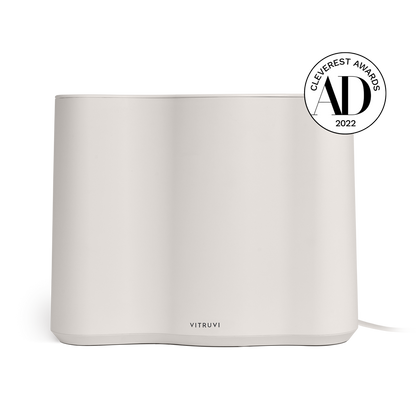 A sleek and minimalist Vitruvi Cloud Humidifier in a clean white finish is pictured. It boasts a smooth, curved design and utilizes ultrasonic technology. In the top right corner, there is a black badge that reads "Cleverest Awards 2022." The Vitruvi logo is prominently displayed at the bottom front.