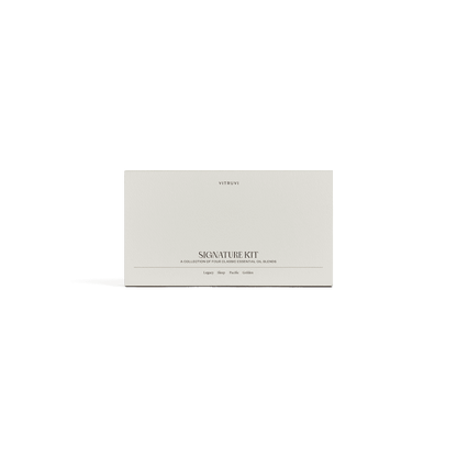 A minimalist white box featuring the brand name "Vitruvi" and the product name "Signature Diffuser Blend Kit" is accompanied by a subtitle highlighting its role as a collection of essential oil blends for relaxation and stress relief. The clean design includes a shadow beneath the box, all set against a solid green background.