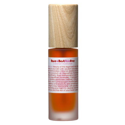 A small amber bottle with a beige wooden cap, labeled "Best Skin Ever Cleanser - Rose" in red text by Living Libations. The label also contains a detailed product description and a list of natural ingredients. Ideal as a face and body moisturizer.