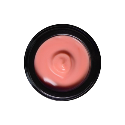 A top-down view of an open jar reveals a smooth, pink-colored Rose Glow Crème. The jar has a black rim, and the cream appears freshly used with a small dip in the center. This luxurious botanical moisturizer by Living Libations promises nourishment, infused with rose hydrosol for added benefits. The background is transparent.
