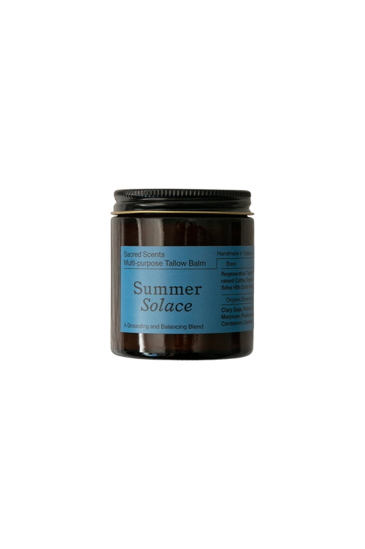 A jar of Summer Solace Tallow's Sacred Scents Spiritual Balm - Regenerative Tallow® is displayed against a black background. The jar features a dark body with a blue label and a black lid. Text on the label includes "Sacred Scents," "Handmade in California," and various ingredients and uses like hormone balancing.