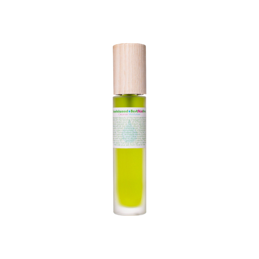 A glass bottle containing green liquid, capped with wood, and adorned with a label featuring colorful text. This elegant bottle houses the Best Skin Ever Cleanser- Sandalwood from Living Libations, likely a scented or cosmetic product infused with essential oils.