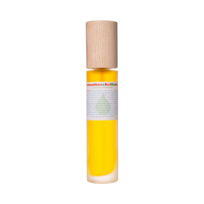 A transparent cylindrical bottle with a wooden cap, filled with a yellow liquid that is likely organic oils or serum. The bottle features a white label with text and a green emblem highlighting Seabuckthorn. It contains the Best Skin Ever Cleanser - Seabuckthorn by Living Libations.